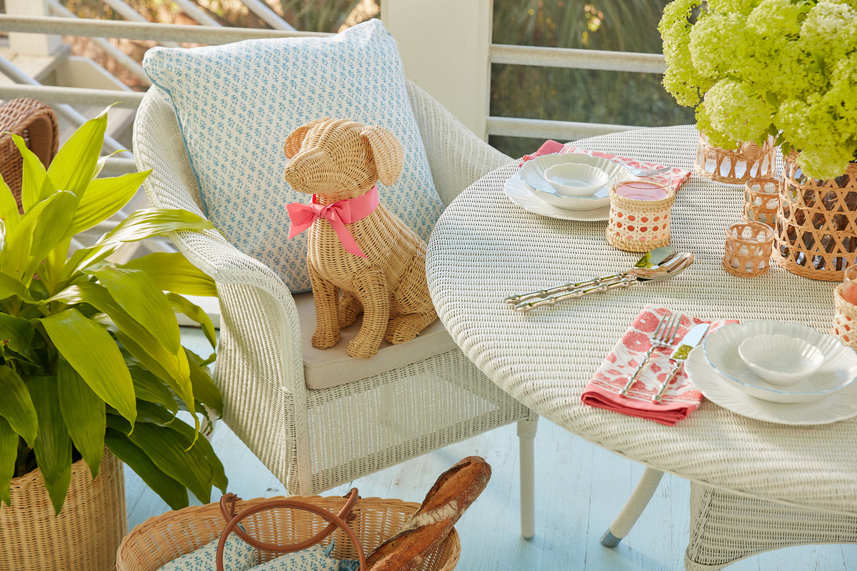 Potcake Wicker Dog (Large) by Amanda Lindroth shown in chair at patio table