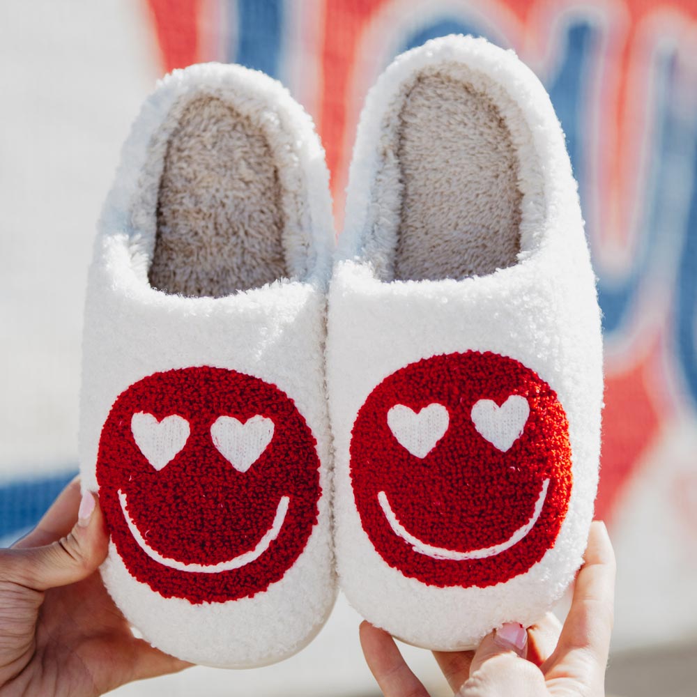 Heart Eyes Red Happy Face Slippers from Katydid have white heart shaped eyes, red happy face on white Sherpa and rubber soles