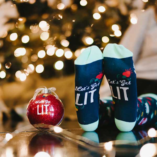 Let's Get Lit Holiday Socks and Ornament girl wearing socks next to ornament lifestyle image