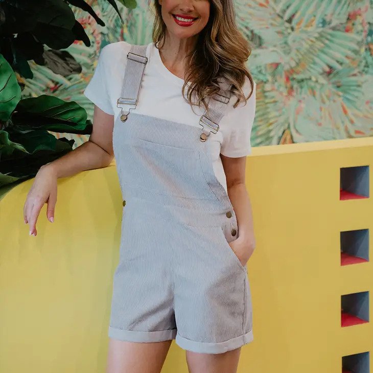 Light Grey Women&#39;s Corduroy Overalls worn by model wearing white tee leaning against yellow wall