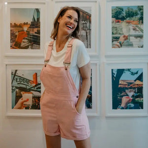 Light Pink Corduroy Overalls worn by model wearing a white tee in an art gallery