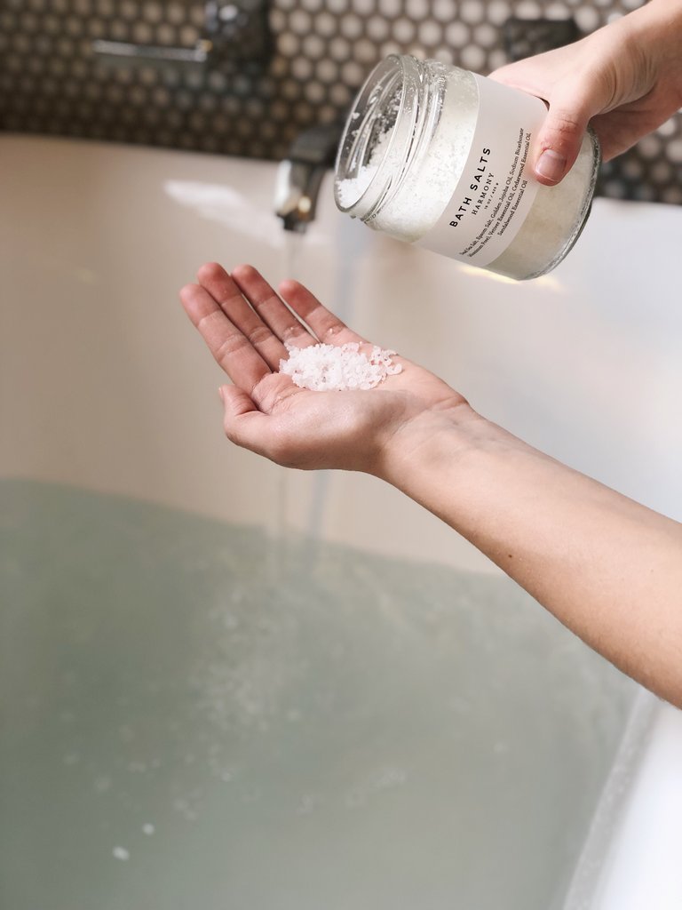 Image of pouring bath salts into palm of hand to add to warm bath