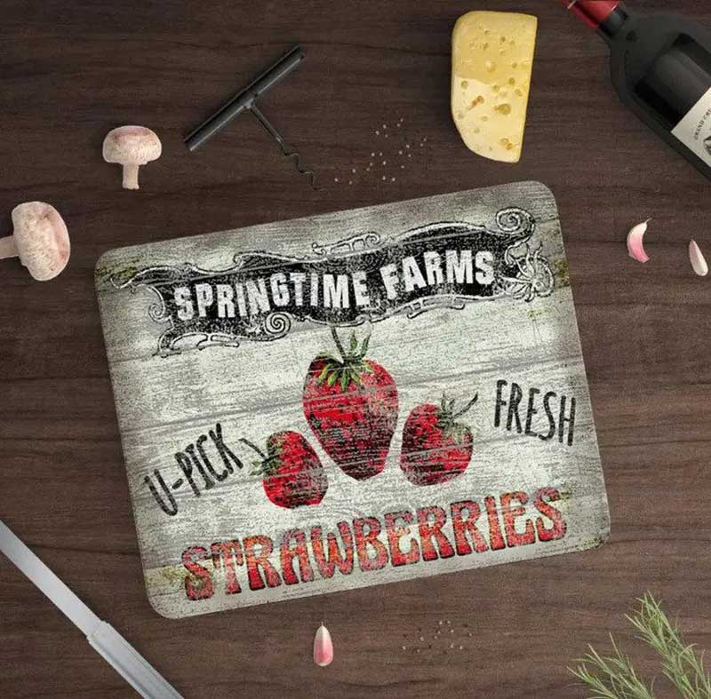Strawberry Farm Kitchen Cutting Board displayed on table with food and wine bottle