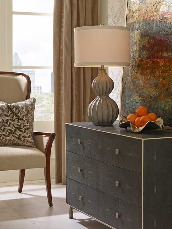 Delphine table lamp with modern style fluted gourd composite base from Wildwood shown on dresser