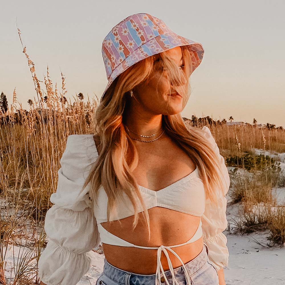 Daisy Graphic Bucket Hat worn by young woman along beach dunes